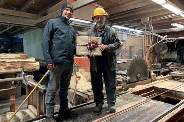 Deux hommes dans une scierie avec un cadeau.