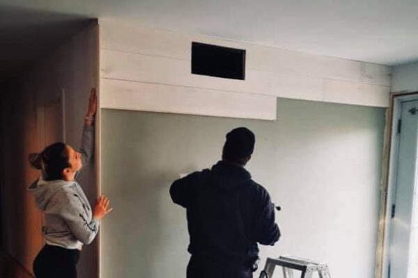 Rénovation murale avec deux personnes et une échelle.