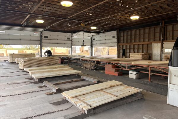 Intérieur d'un entrepôt de bois avec planches empilées.