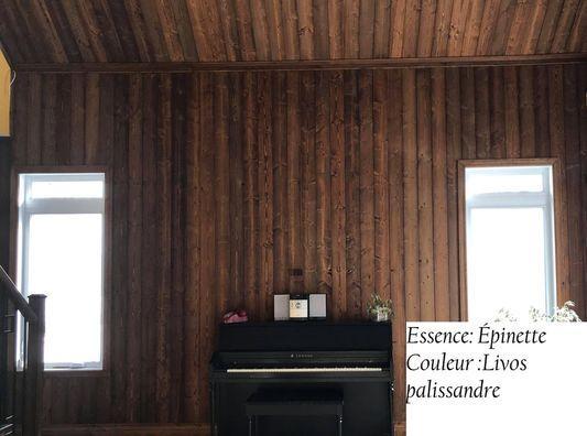 Salon en bois avec un piano et fenêtres.