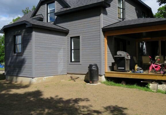 Maison grise avec terrasse et barbecue modern.