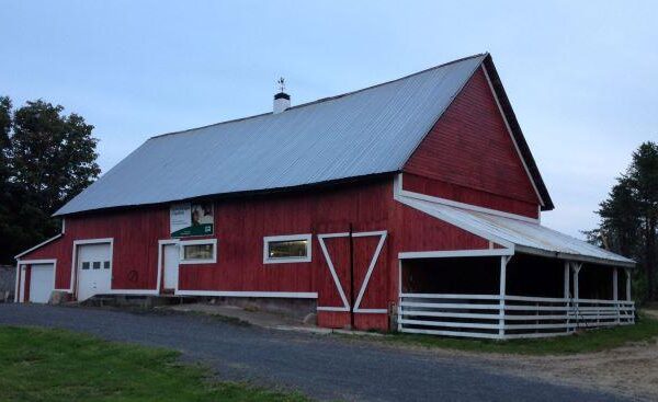 Grande grange rouge avec toit métallique gris.